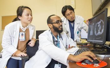 corp-residents_1 three doctors examine an x-ray on a computer screen