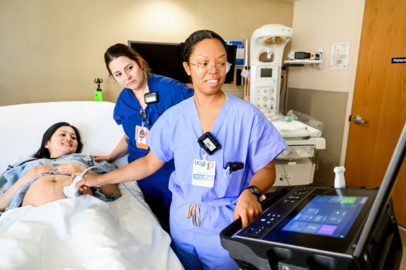 A doctor and a nurse, both female, assist a pregnant woman during an ultrasound