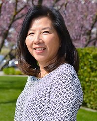 LeeAnn Cunningham, RN, poses in front of a field of blossoming trees