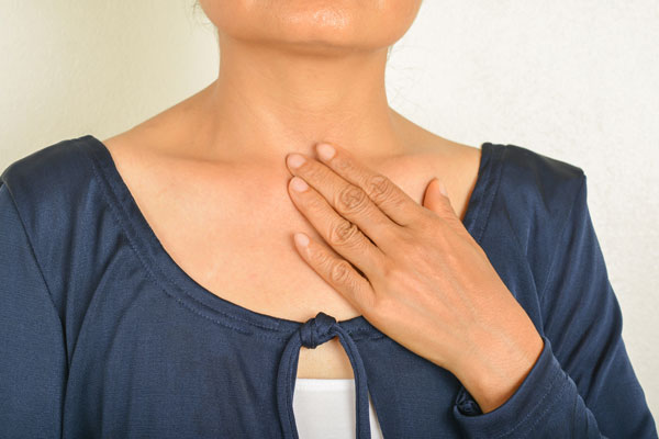 Close up of a white woman holding her fingers to her throat