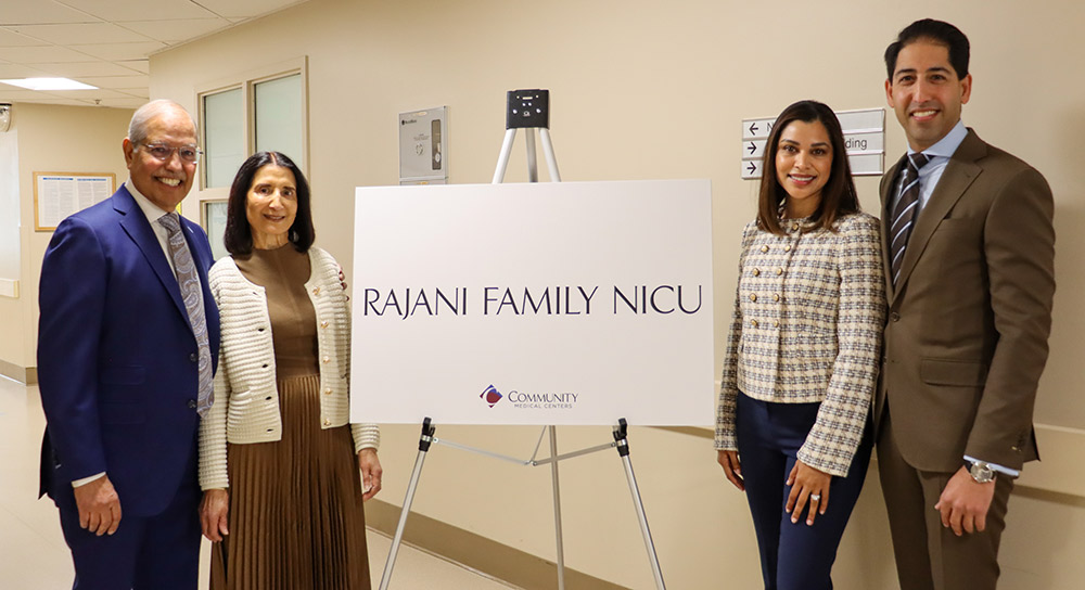 Four people, two on each side, frame a sign that reads, "Rajani Family NICU"