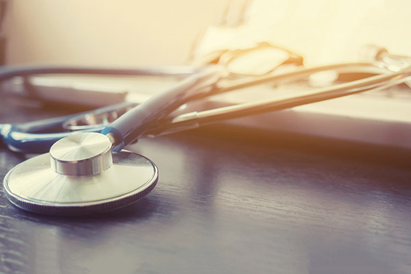 Close up of a silver stethoscope resting on a desk.