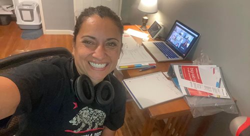 A smiling Gordie Ochinero-Bermundez sits at her home desk in front of a computer.