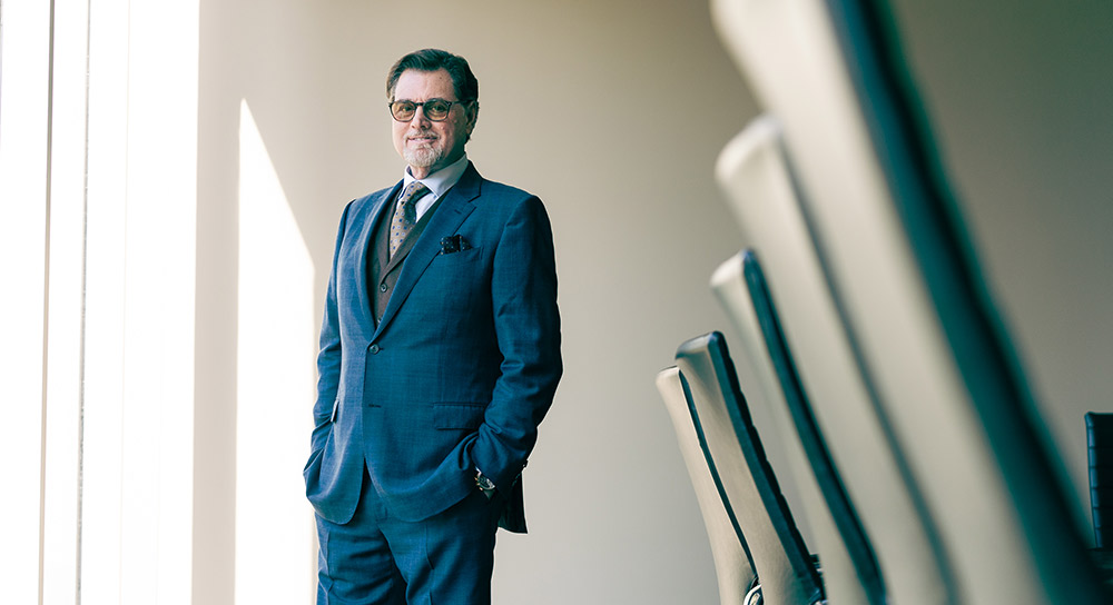 Craig Wagoner stands in a conference room between wide windows and a conference table with chairs in close-up.